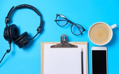 Music or podcast background with headphones, microphone, coffee and blank on blue table, flat lay. Top view, flat lay